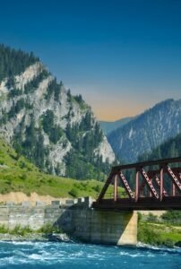 a bridge over a river with mountains in the background